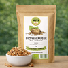Bio Walnüsse Bruch naturbelassen von Awesome Nuts im Beutel neben einer Schale mit Walnussbruch auf Holztisch vor grünem Naturhintergrund