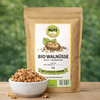 Bio Walnüsse Bruch naturbelassen von Awesome Nuts im Beutel neben einer Schale mit Walnussbruch auf Holztisch vor grünem Naturhintergrund

